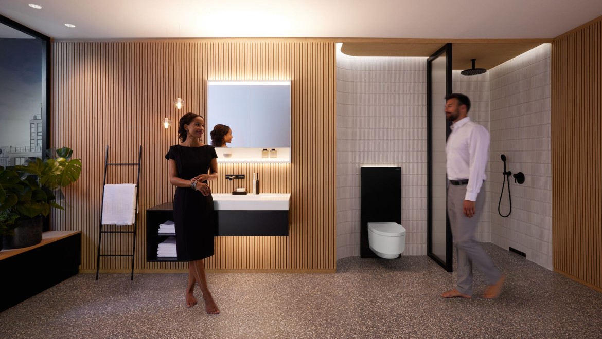 Homem e mulher numa casa de banho perfeitamente iluminada com produtos Geberit ONE Homem e mulher numa casa de banho perfeitamente iluminada com produtos Geberit ONE