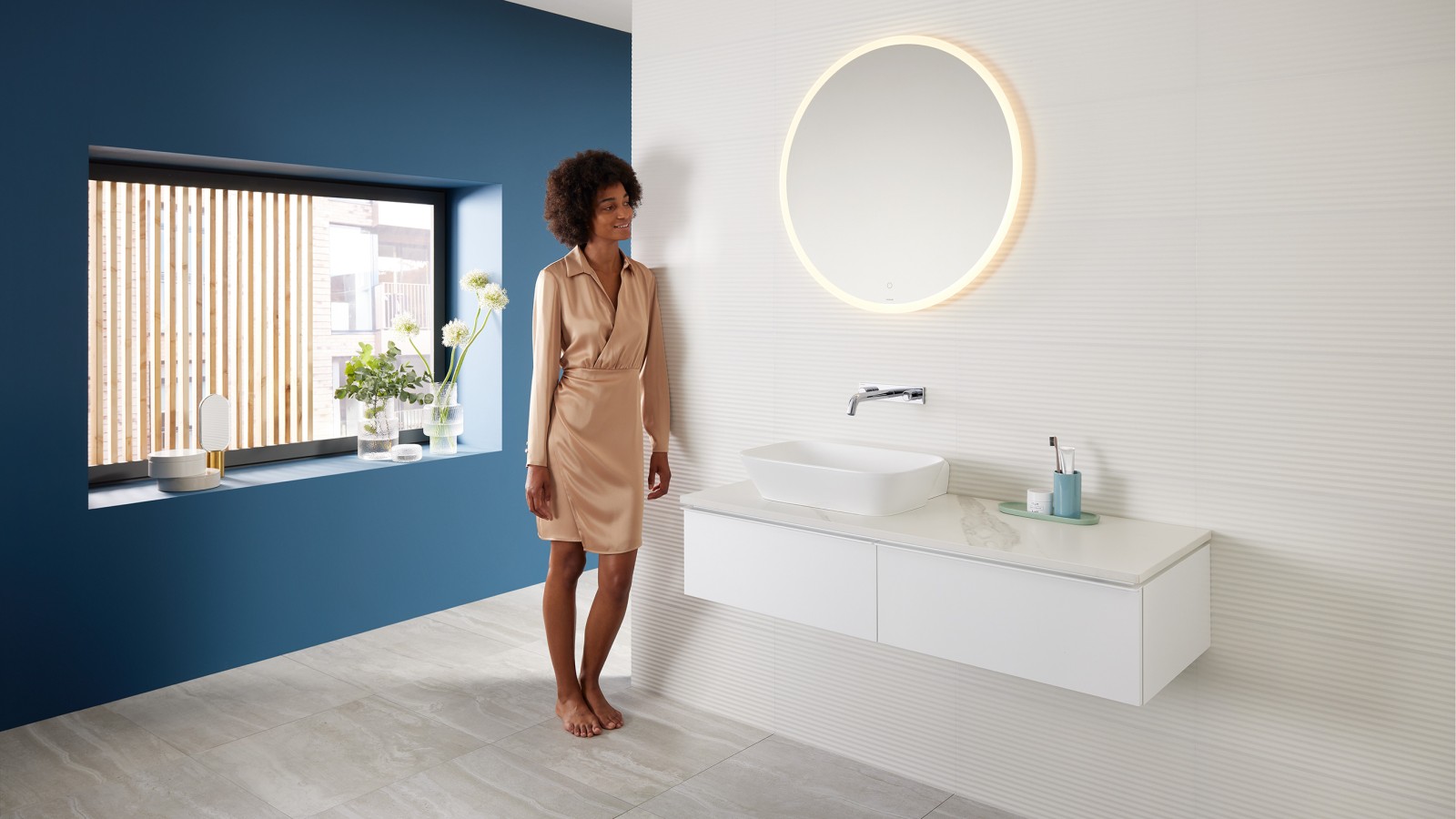 Mulher encostada à parede da casa de banho com produtos da gama Geberit Mix & Match Mulher encostada à parede da casa de banho com produtos da gama Geberit Mix & Match