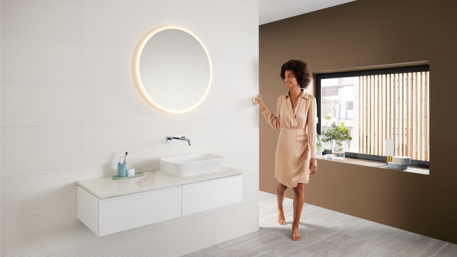 Mulher numa casa de banho moderna com um esquema de cores castanhas – a última tendência em cores para casas de banho – e uma combinação Mix & Match na zona do lavatório. Mulher numa casa de banho moderna com um esquema de cores castanhas – a última tendência em cores para casas de banho – e uma combinação Mix & Match na zona do lavatório.