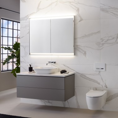 Casa de banho com parede em azulejos efeito mármore, lavatório e móvel Geberit ONE e armário de espelho com luz ComfortLight Casa de banho com parede em azulejos efeito mármore, lavatório e móvel Geberit ONE e armário de espelho com luz ComfortLight