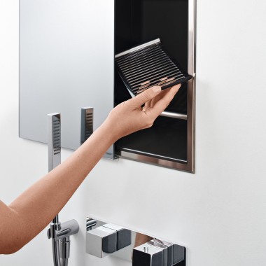 Mão de mulher a colocar uma estante na caixa de arrumação do nicho no duche (© Geberit)