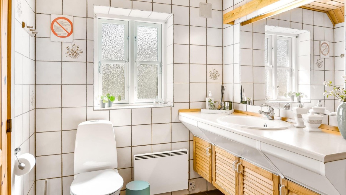 Casa de banho original com sanita de chão, azulejos brancos e mobiliário de casa de banho em madeira (© @triner2 e @strandparken3)