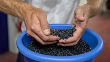 Mãos a segurar bolinhas de plástico pretas (© Ben Huggler)