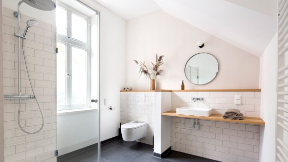 Nas casas de banho instalou-se o lavatório Geberit ONE e as torneiras de parede ONE. A sanita com sistema integrado de lavagem Geberit AquaClean Sela oferece aquele toque extra de conforto (© Geberit) Nas casas de banho instalou-se o lavatório Geberit ONE e as torneiras de parede ONE. A sanita com sistema integrado de lavagem Geberit AquaClean Sela oferece aquele toque extra de conforto (© Geberit)