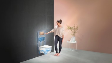 Mulher que acciona a descarga da Solução Completa Geberit (© Geberit)