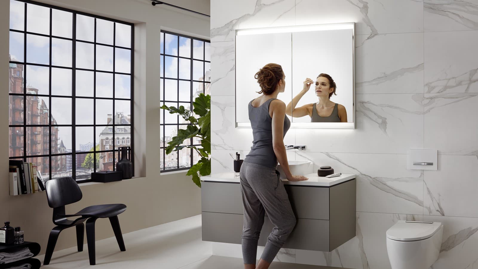 Mulher numa casa de banho da série Geberit ONE, com o lavatório instalado à altura ideal Mulher numa casa de banho da série Geberit ONE, com o lavatório instalado à altura ideal