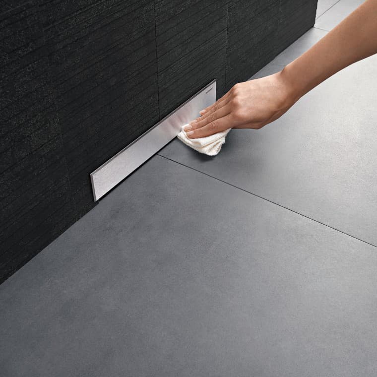 Uma mão limpa a tampa de um sifão de parede da Geberit Uma mão limpa a tampa de um sifão de parede da Geberit