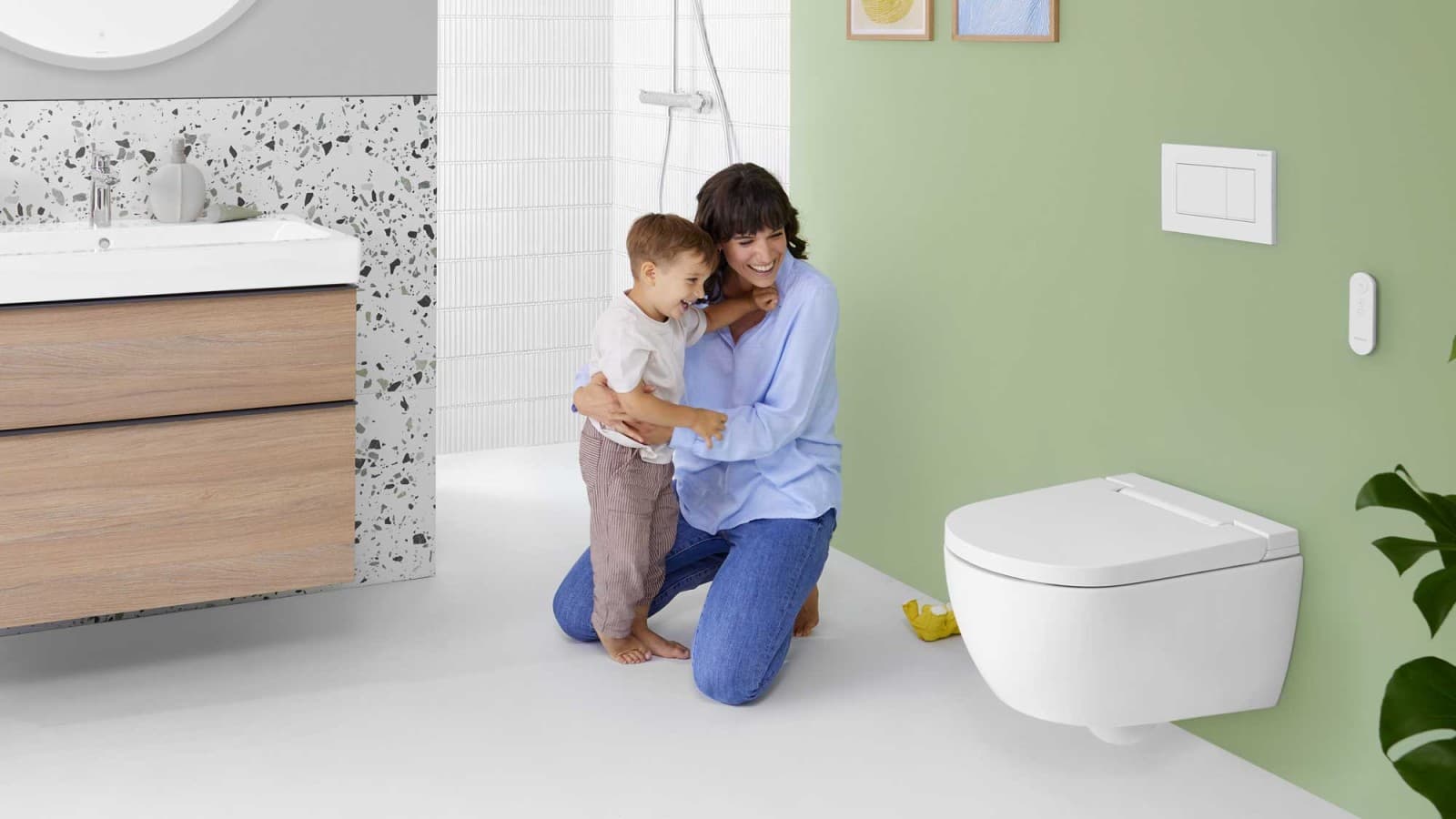 Mulher com uma criança em frente a uma sanita bidé Geberit AquaClean Alba Mulher com uma criança em frente a uma sanita bidé Geberit AquaClean Alba