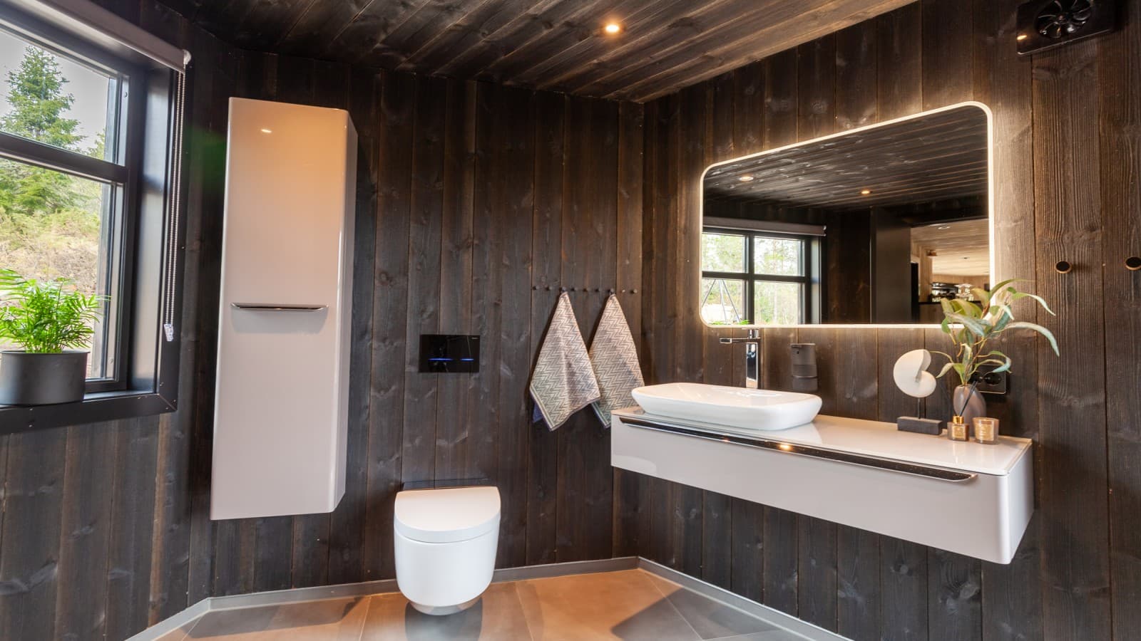 A casa de banho também está revestida a madeira e, para além da sanita bidé AquaClean Mera, existem outros produtos Geberit lá instalados (© Geberit) A casa de banho também está revestida a madeira e, para além da sanita bidé AquaClean Mera, existem outros produtos Geberit lá instalados (© Geberit)