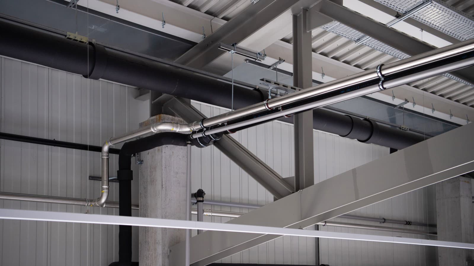 O sistema Geberit Mapress Aço Inoxidável para diversos fluidos, como gás, ar comprimido e refrigeração, foi instalado por cima das máquinas de produção O sistema Geberit Mapress Aço Inoxidável para diversos fluidos, como gás, ar comprimido e refrigeração, foi instalado por cima das máquinas de produção